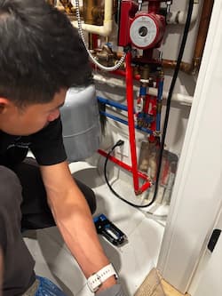 Technician performing pest exclusion work by utility piping